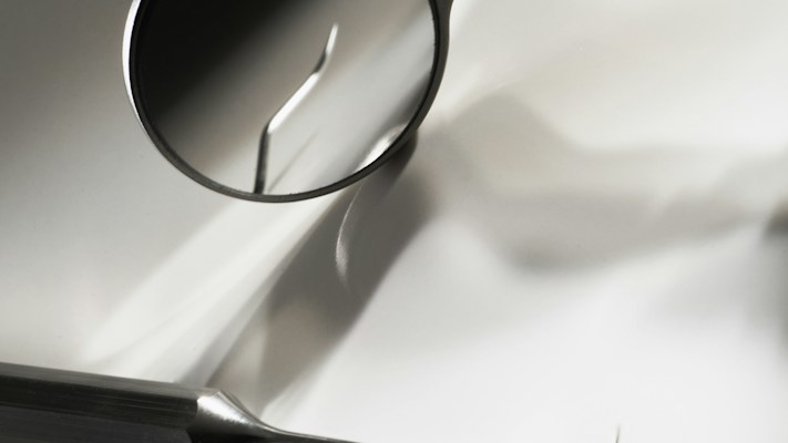 A dental mirror and examination instrument on a white surface